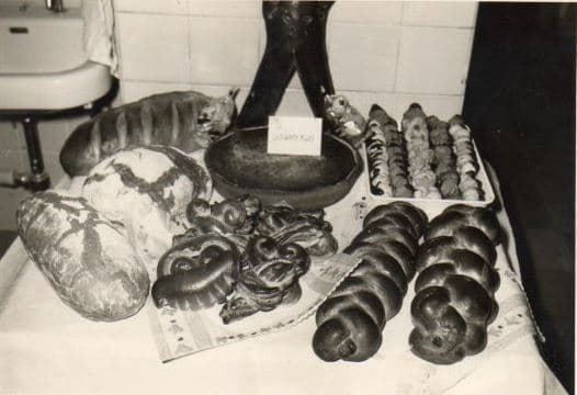 Schwarz-weiß-Aufnahme einer Auslage mit Stollen, Hefezöpfen und Kringeln
