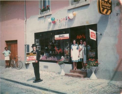 Eröffnung des Tchibo-Cafés mit Charlie-Chaplin-Aufsteller und Familie vor dem Laden