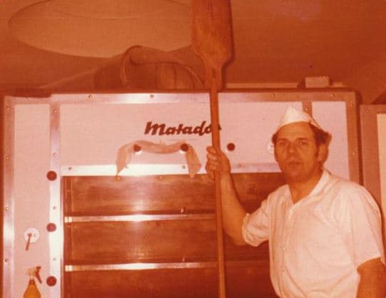 Bäcker mit Brotschaufel am Matador-Ofen, sepia-getönte Aufnahme